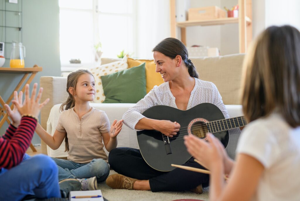 Crianças em aula de música com professora, ilustrando os benefícios do aprendizado musical infantil